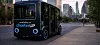 CharterUP-branded autonomous shuttle bus drives on an empty city street at dusk.