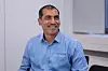 Smiling man in an FPT Germany shirt sitting in a bright office.