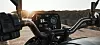 Motorcycle handlebar and digital dashboard against a desert sunset backdrop