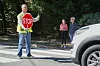 Crossing guard with stop sign stopping a car at a zebra crossing