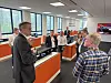 Group listens to a presentation in a bright tech showroom with orange displays.