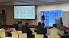 Conference speaker presenting charts on a screen to seated attendees