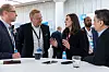 Professionals in a conference room talking around a table during a networking event.