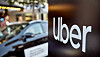 Uber logo on a dark sign with a blurred car and city street in the background.
