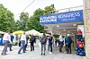 People enter a conference venue beneath a blue Automobil Elektronik Kongress banner beside balloon decorations.