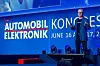 Presenter standing on a stage in front of a large blue conference screen.