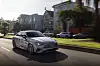 Mercedes-Benz CLA 250+ with EQ Technology driving past houses on a sunny suburban street.