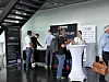 Attendees standing at a trade show booth with LED product displays and branded banners.