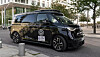 Black Volkswagen electric van parked on a city street near glass-fronted buildings.