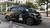 Black Volkswagen electric van parked on a city street near glass-fronted buildings.