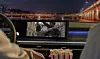 Car interior with dashboard screen playing a film and popcorn in the foreground.