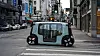A small autonomous vehicle stopped at a crosswalk on a city street.