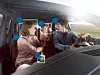 People inside a car with facial recognition icons overlaid on the image.