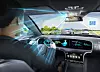 Rear-seat view of a car driving toward a checkpoint on a multi-lane road with digital dashboard screens.