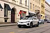 White electric SUV driving past historic buildings on a city street.