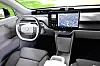 Electric car cabin with a yoke steering wheel and large central display.