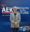 Man standing in front of a blue AEK welcome-to-the-future exhibition backdrop.