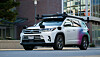 White police SUV parked on a city street beside a glass-fronted building.
