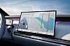Car dashboard with a large touchscreen showing navigation maps and driving data.
