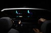 Dark car cabin with two glowing dashboard displays and occupants in the front seats.