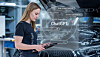 Woman holding a tablet beside a car with a ChatGPT graphic overlay.