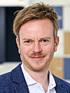 Portrait of a man wearing a blue blazer and white shirt indoors.