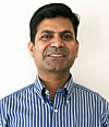 Portrait of a man wearing a blue-and-white striped shirt against a plain white background.