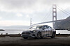 Mercedes-Benz sedan parked beside the water with the Golden Gate Bridge behind it.