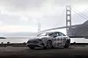 Mercedes-Benz sedan parked beside the water with the Golden Gate Bridge behind it.