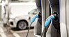 Charging plugs connected to electric vehicles at a station.