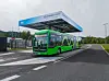 Green Mercedes-Benz eCitaro bus parked under a charging canopy in Ljubljana.